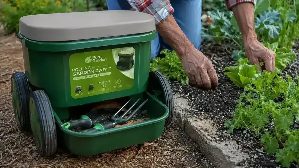 Close-up of the Pure Garden rolling cart seat with tool tray visible, parked beside a row of vegetable plants