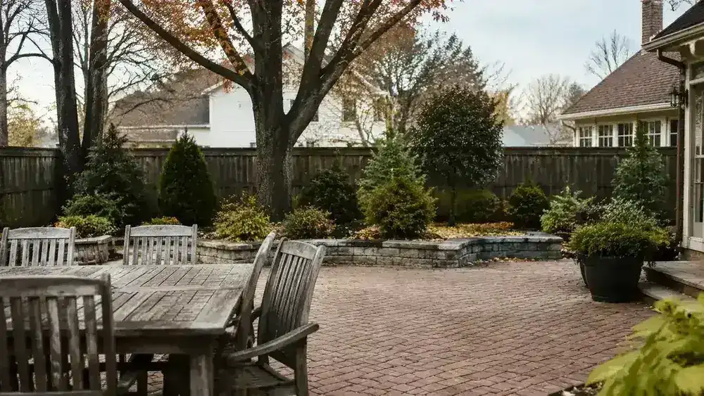 Backyard leaf cleanup scene showing cleared patio and remaining leaf piles near garden beds